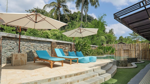 A patio with stone steps, lounge chairs, and umbrellas. - Attara Inn Senggigi (Senggigi)