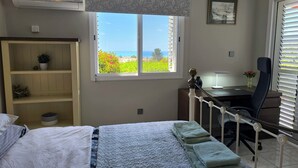 Ett sovrum med en säng, ett skrivbord, en stol, ett fönster med utsikt och en garderob.