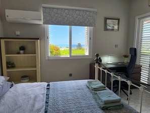 Une chambre à coucher comprenant un lit, un bureau, une chaise, une fenêtre avec vue et une armoire.