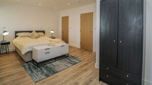 A bedroom with a bed, bedside tables, a wardrobe, and a door. - The Studio (Weston-super-Mare)