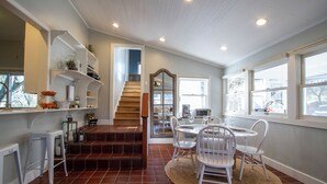 A dining area with a round table, white chairs, and a staircase leading to another level. - Country chic cottage and connected water tower next to Jordan winery (Healdsburg)