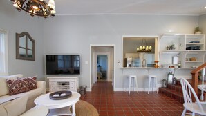 A living room with a TV, sofa, and coffee table. There is a kitchen area with a fridge and a dining area with chairs. - Country chic cottage and connected water tower next to Jordan winery (Healdsburg)
