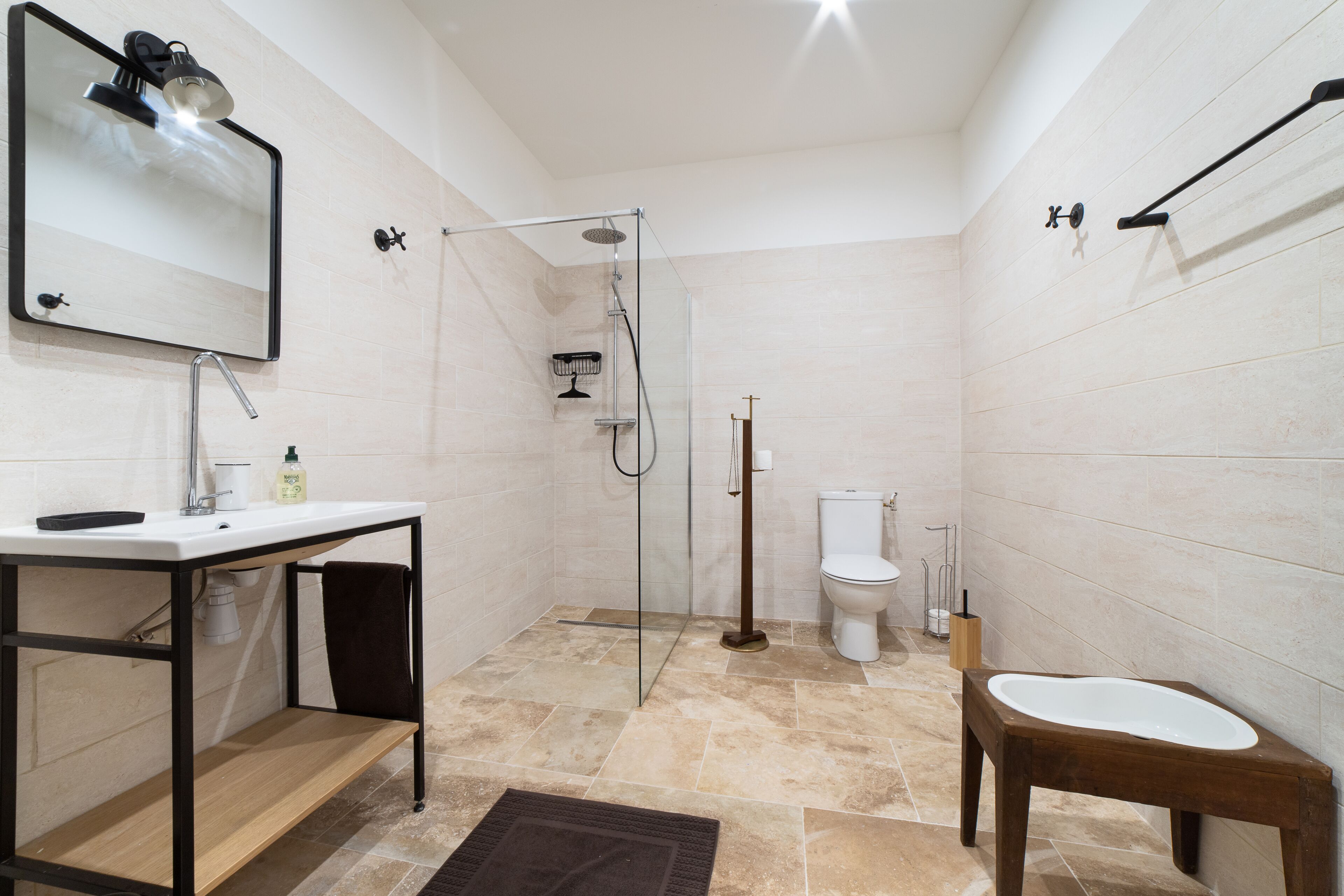 A modern bathroom with a glass-enclosed shower, a toilet, and a sink with a mirror above it.