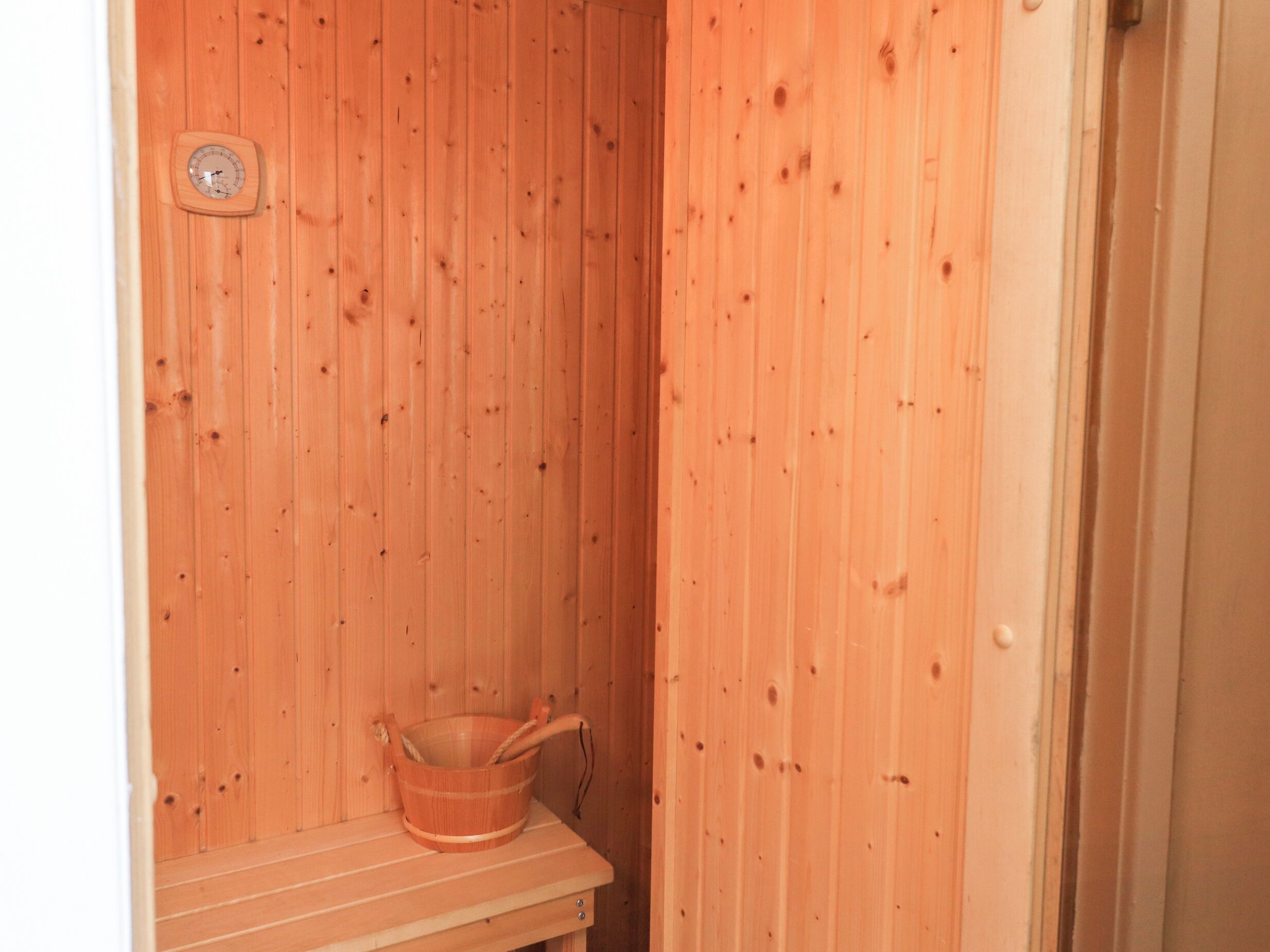 A wooden sauna with a wooden bench and a wooden bucket.