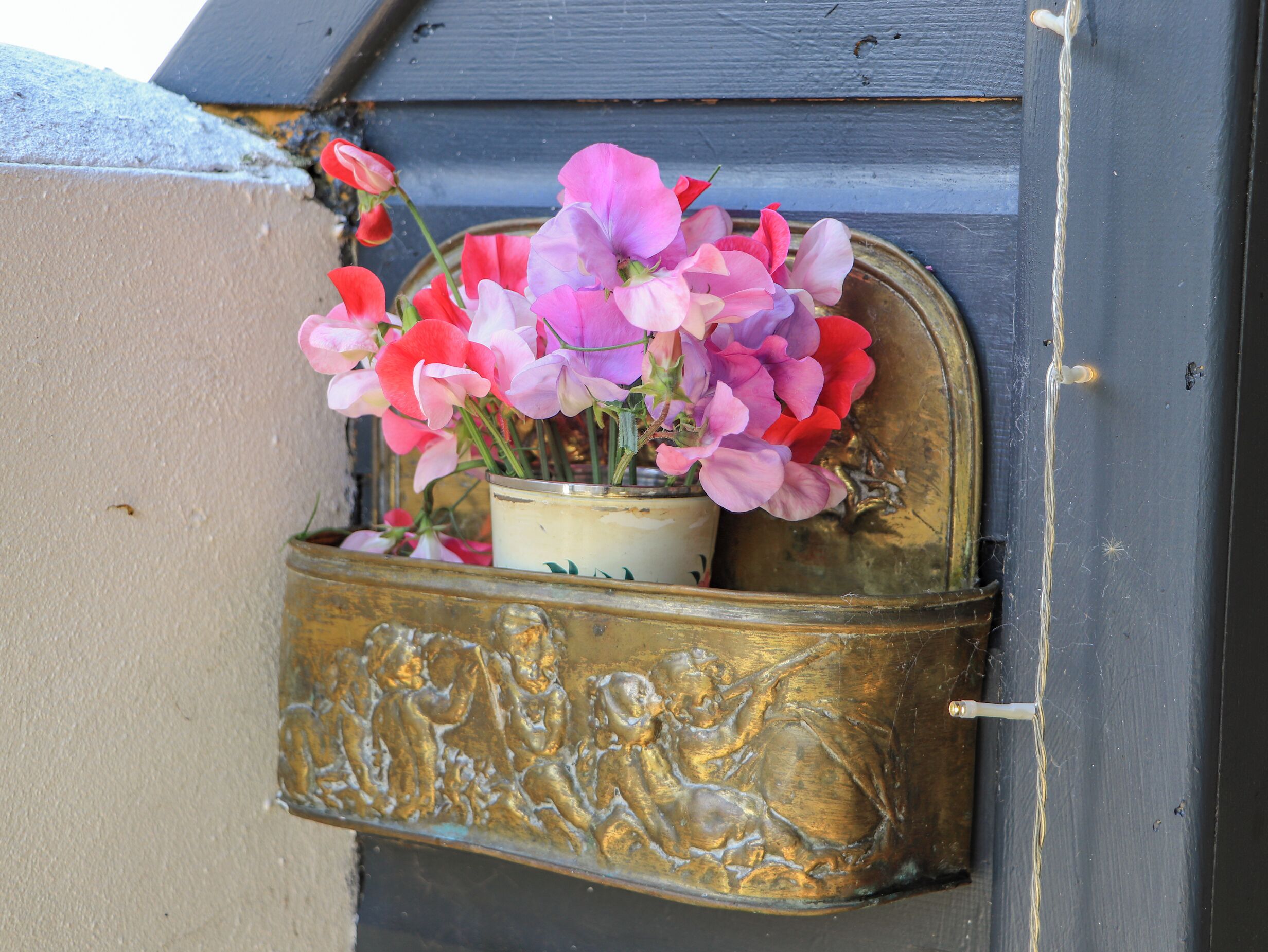 A brass mailbox with a floral arrangement.