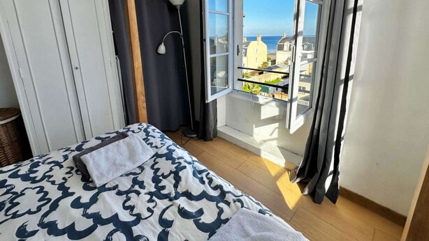 Ein Schlafzimmer mit Bett, Fenster mit Meerblick und Kleiderschrank.