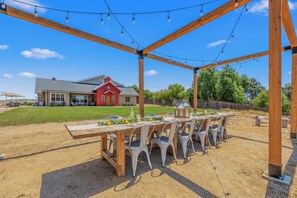An outdoor patio with a wooden pergola, string lights, and a table set for dining. - Cooperage by AvantStay | Vineyard, Views, Soccer (Paso Robles)