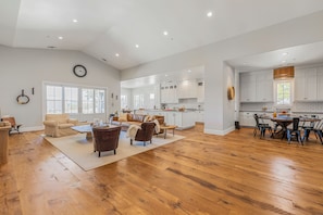 A spacious living area with a large wooden floor, a sofa set, and a dining table with chairs.