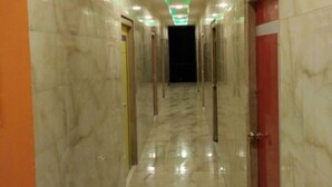 A marble-floored corridor with green underglow lighting, doors on both sides, and a dark end. - Hotel Royal Palace (Port Blair)