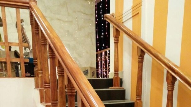 A wooden staircase with a curved handrail leading to a landing. - Hotel Royal Palace (Port Blair)