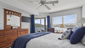 A bedroom with a bed, a dresser, a television, and a ceiling fan.