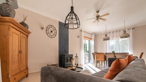 A cozy living room with a grey sofa, wooden cabinet, and a fireplace. - Comfy house with large garden and swimming pool (Folques)