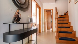 A modern interior with a black console table, a wooden staircase, and a decorative motorcycle figure. - Comfy house with large garden and swimming pool (Folques)