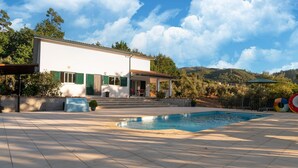 A modern house with a swimming pool, green shutters, and a view of hills. - Comfy house with large garden and swimming pool (Folques)