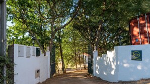 A gated entrance with a dirt path leading to a building, surrounded by trees. - Comfy house with large garden and swimming pool (Folques)