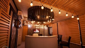 Een receptiegedeelte met een houten plafond, een ronde lamp en een televisiescherm.