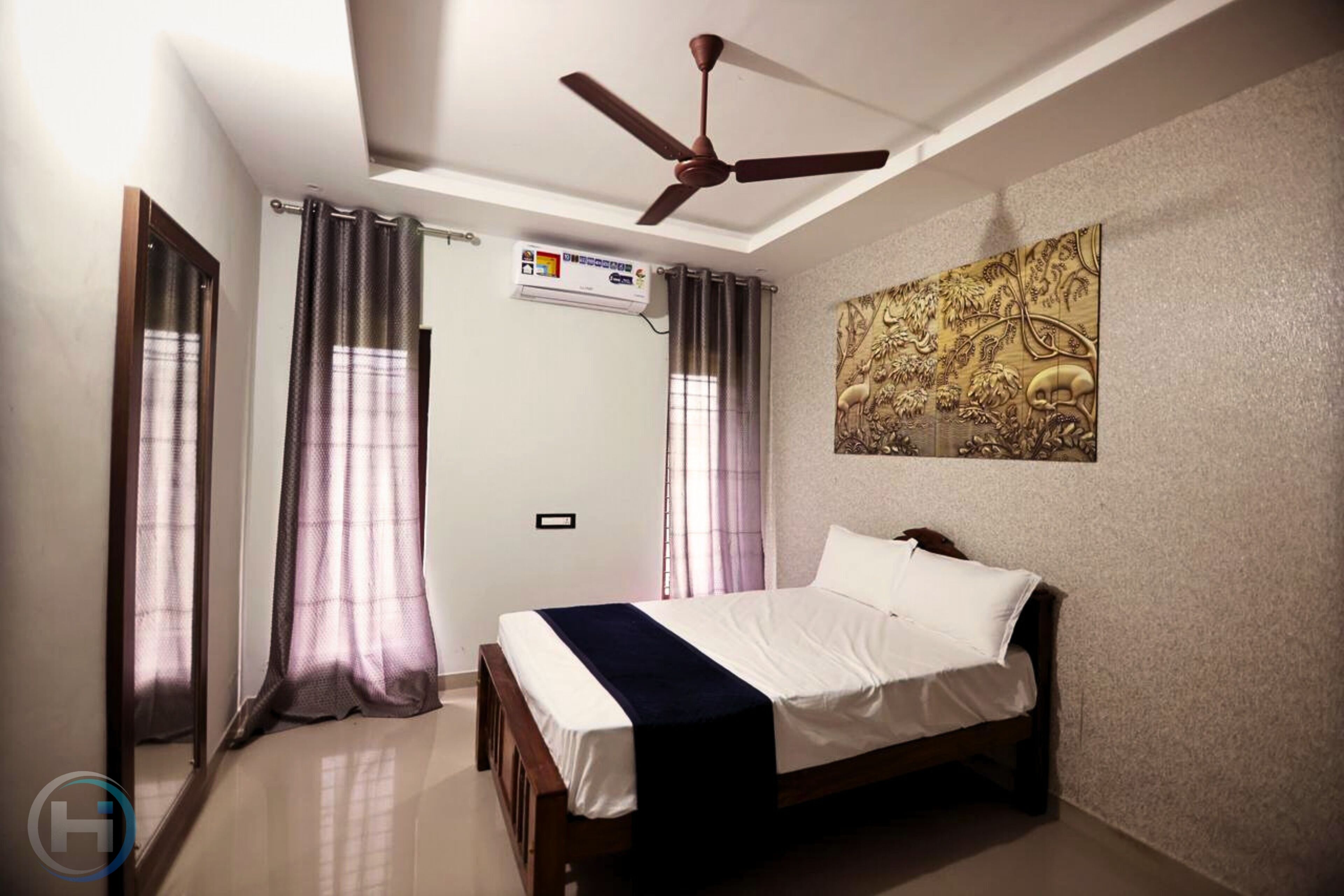 A bedroom with a bed, ceiling fan, air conditioning unit, and decorative wall art.