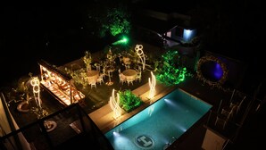 Een buitenzwembad met zitplaatsen en sfeerverlichting.