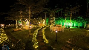 Een tuinpad met stoelen en tafels, verlicht door lichtslingers en lantaarns.