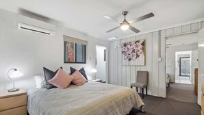 Ein Schlafzimmer mit einem Bett, Nachttischen, einem Deckenventilator und einem großen Spiegel.