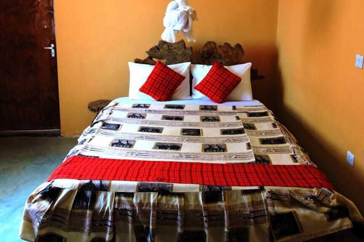 A bed with a patterned bedspread, two red pillows, and a white canopy.