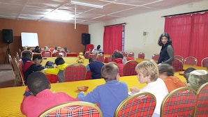 Une salle de conférence avec des tables rondes, des rideaux rouges et un podium à l’avant.