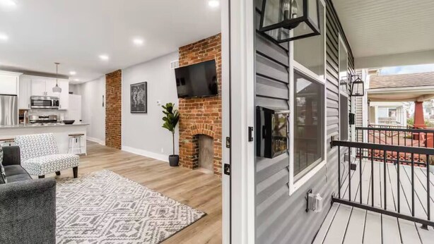 Uma sala de estar moderna com lareira, área de cozinha e varanda com guarda-corrimão.