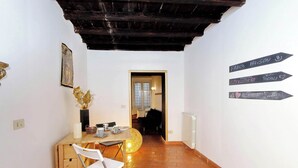 A cozy room with a wooden desk, a white chair, and a small table with decorative items. There are chalkboard signs on the wall indicating directions to various rooms. - Luxury Maison Colosseum, like a resident (Roma)