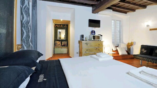 A hotel room with a bed, a wooden dresser, a television, and a sofa. - Luxury Maison Colosseum, like a resident (Roma)