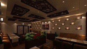 Un restaurante con una barra larga, varias mesas y un techo decorativo.
