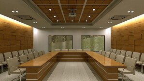 Un salón de conferencias con una larga mesa, sillas y un muro revestido de madera.