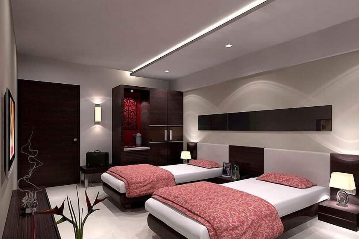 Ein modernes Hotelzimmer mit zwei Betten, einem eingebauten Kleiderschrank, einem Schminktisch mit Spiegel und einem am Wand montierten Fernseher.