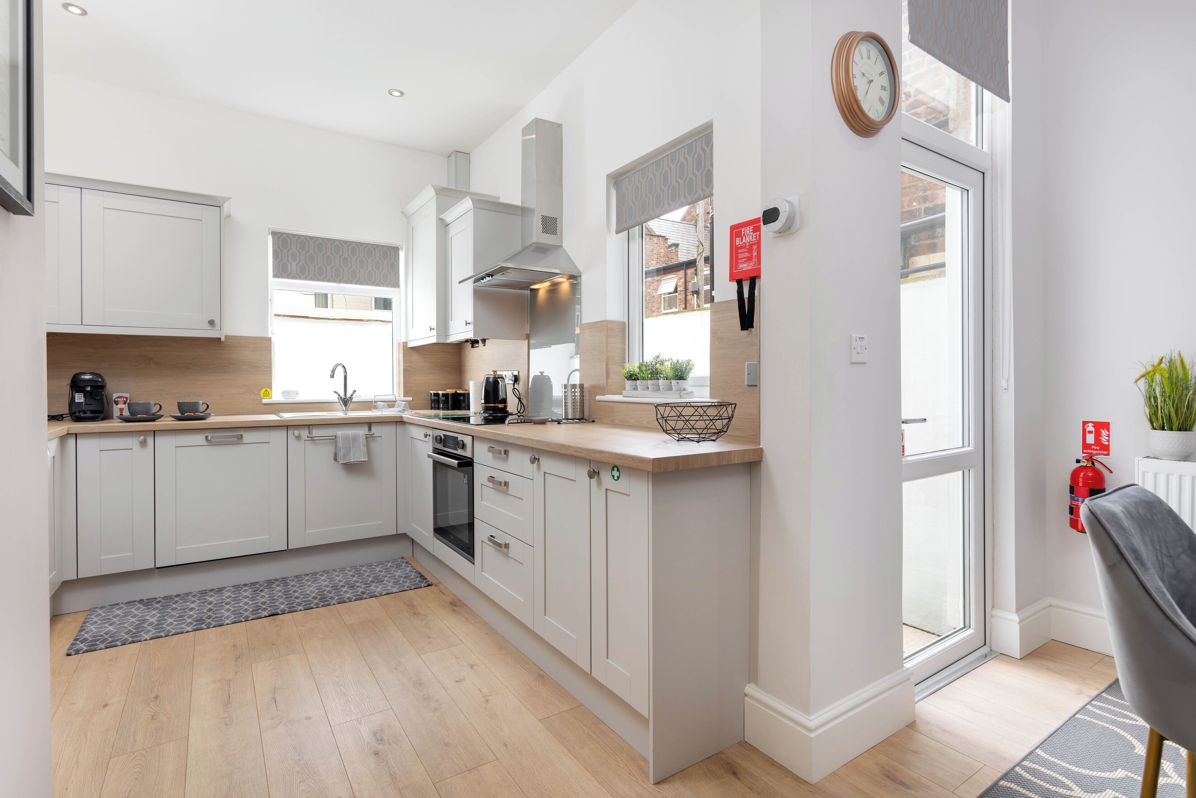 A modern kitchen with white cabinets, a built-in oven, and a window overlooking a brick building.