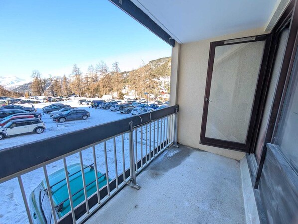 A balcony with a view of a parking lot and snow-covered ground.