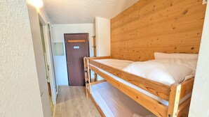 A single wooden bunk bed room with a door and a light fixture.