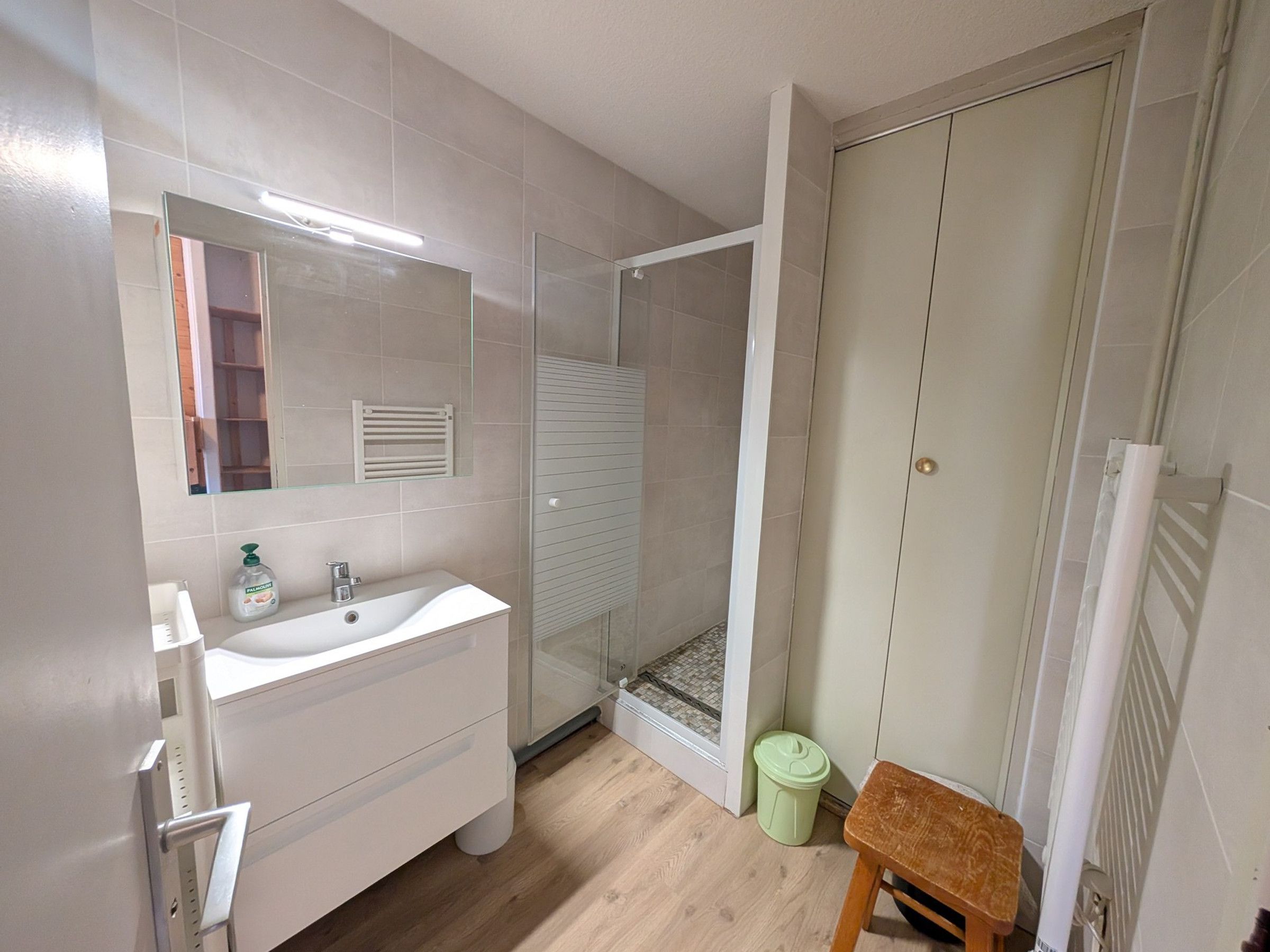 Une salle de bain avec un lavabo blanc, un miroir et une cabine de douche.
