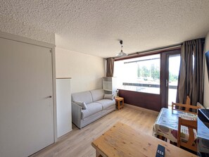 Una habitación con un sofá, una mesita, un ventilador de techo y vistas por una ventana.