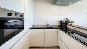 A modern kitchen with a built-in oven, a sink, and a coffee maker. - Flat Sunset - amazing seaview (De Panne)