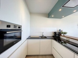 A modern kitchen with a built-in oven, a sink, and a coffee maker. - Flat Sunset - amazing seaview (De Panne)
