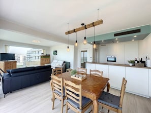 Um apartamento moderno com área de refeições, cozinha e sala de estar.