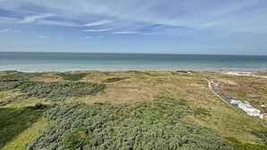 A coastal landscape with a clear sky, a beach, and a row of mobile homes. - Flat Sunset - amazing seaview (De Panne)