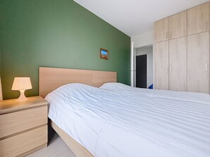 A bedroom with a bed, a nightstand with a lamp, and a wardrobe. - Flat Sunset - amazing seaview (De Panne)