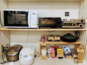 Fully equipped kitchen with microwaves, rice cooker, toaster, and ample storage for food and essentials.