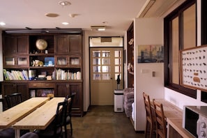 Cozy retreat with a functional layout, featuring a bookshelf, dining table, and microwave.