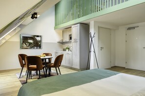 A bedroom with a bed, a dining area with chairs and a table, a kitchenette, and a balcony with a railing. - Somerset Schoenbrunn Vienna (Vienna)