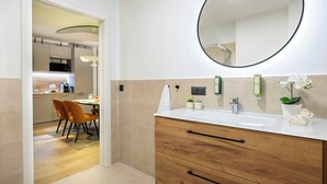 A modern bathroom with a wooden vanity, a round mirror, and a sink. - Somerset Schoenbrunn Vienna (Vienna)