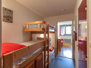 Quarto com beliches, janela, porta e um pequeno corredor.