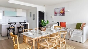 Een moderne keuken met witte kasten, zwarte stoelen en een eettafel gedekt voor zes personen.
