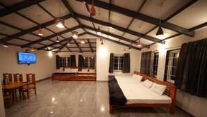 Una habitación amplia con una cama grande, una mesa de comedor con sillas y un televisor colocado en la pared.