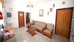 Una sala de estar con un juego de sofá, una mesa de centro, una araña, un reloj y una puerta con un letrero.